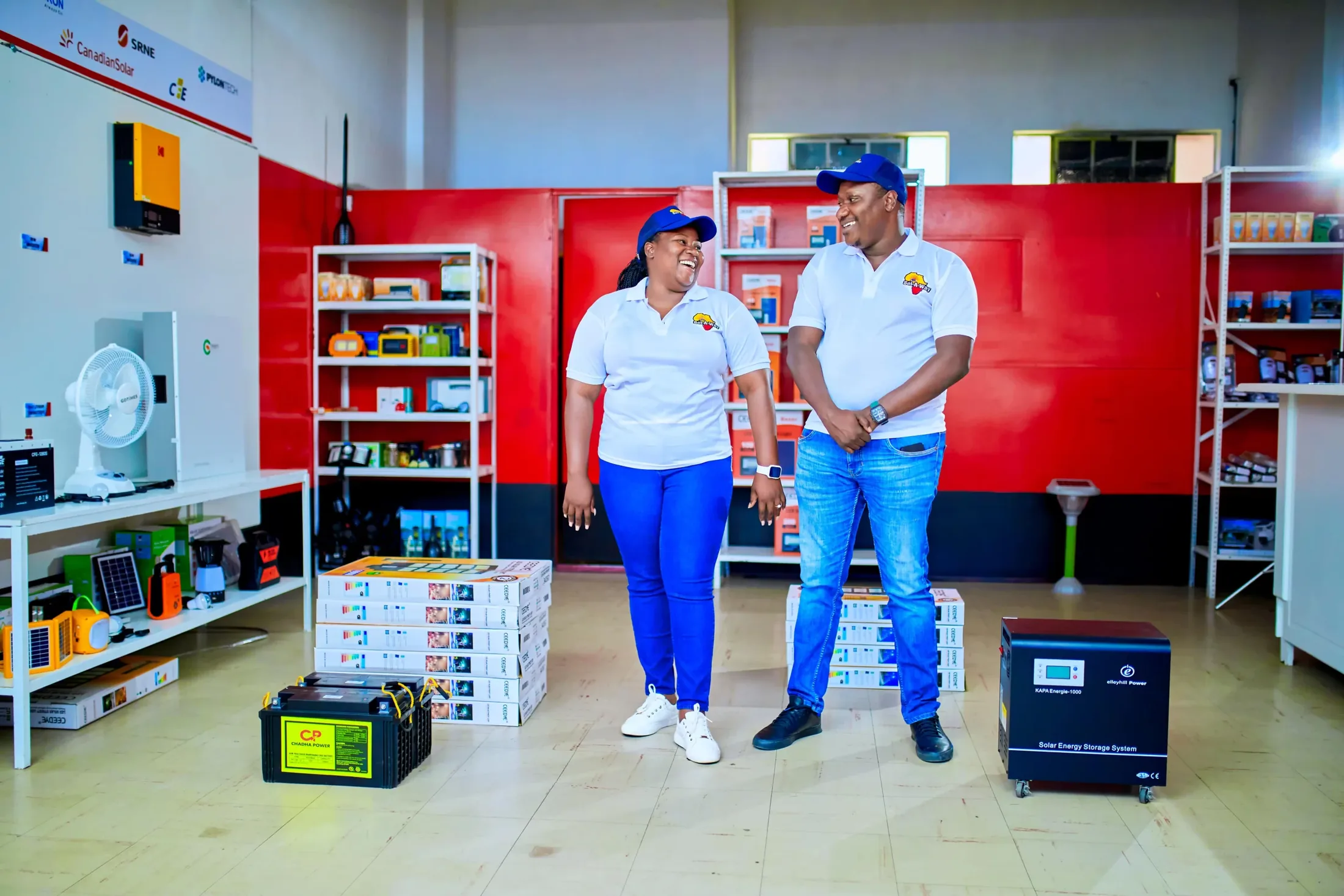 Two Sol-A-Way team members in branded shirts and caps laughing together in the showroom
