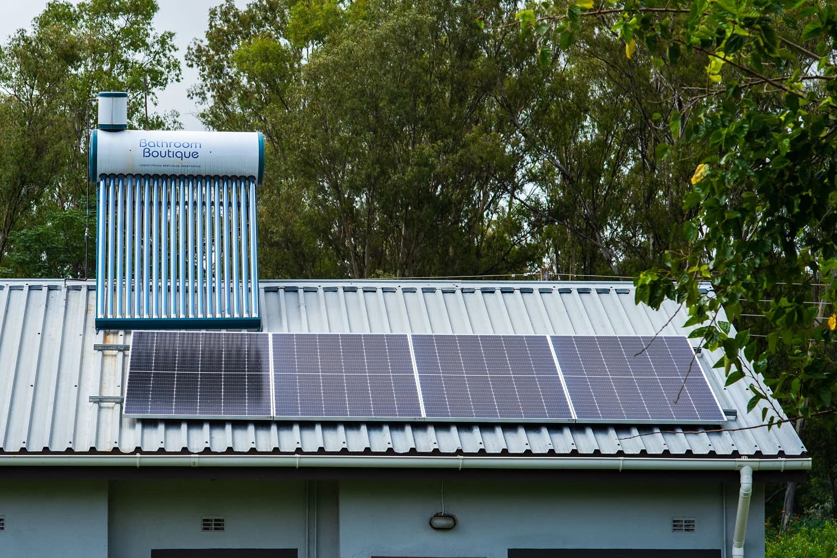 Solar panels beside a solar geyser on a tin roof