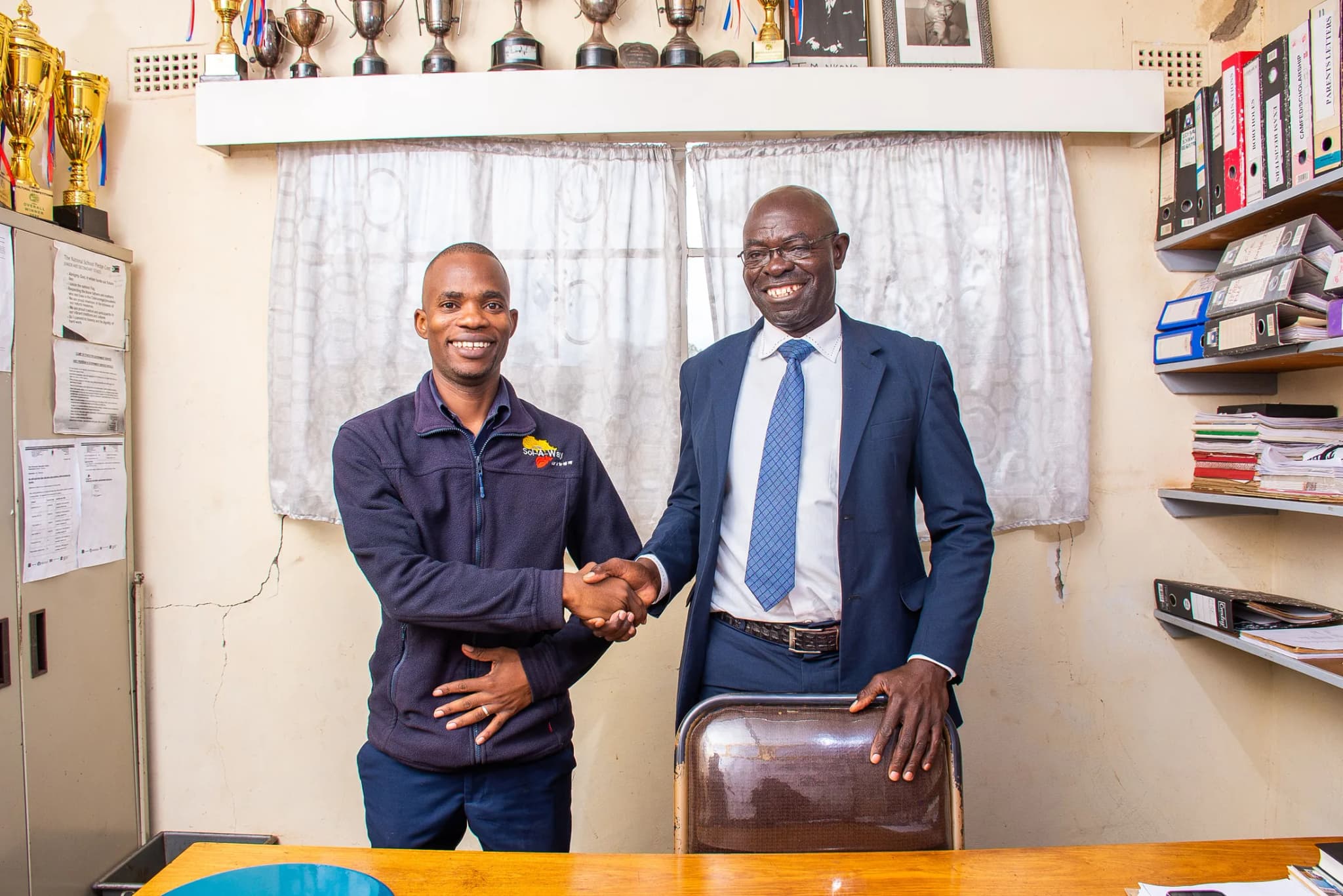 Sol-A-Way and the school head shaking hands in the school office